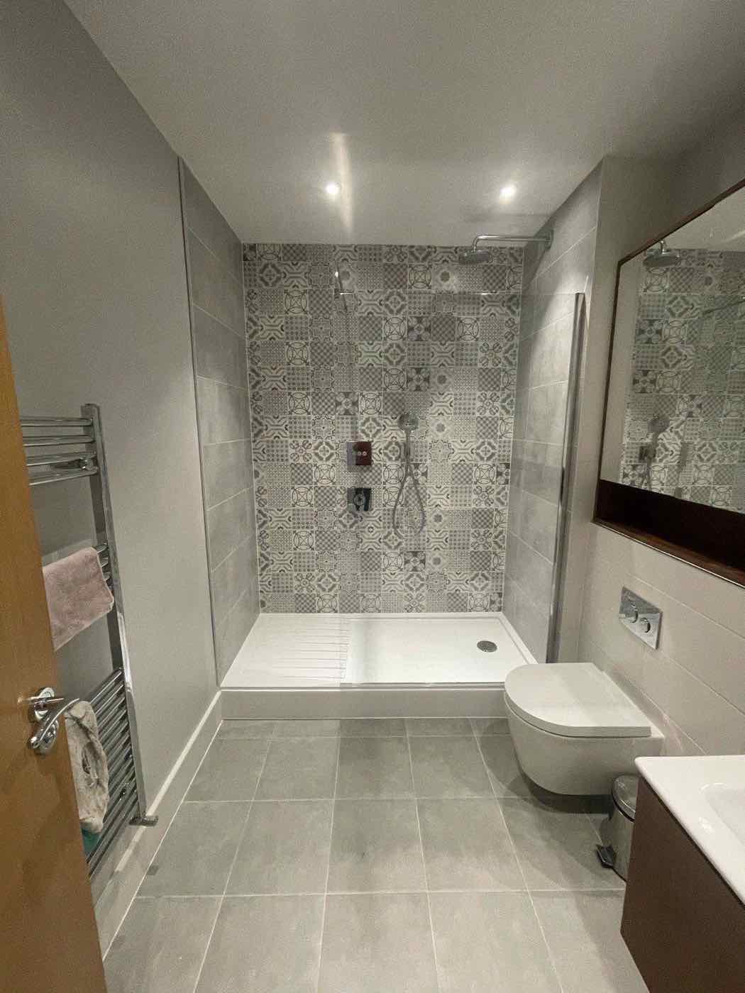Finished bathroom with bath and patterned feature tiling