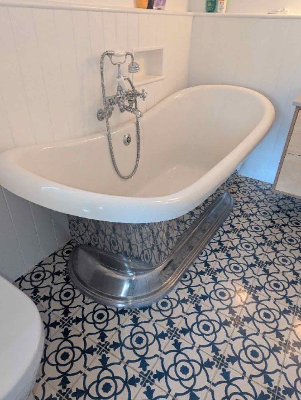 Roll-top bath on a patterned tiled floor
