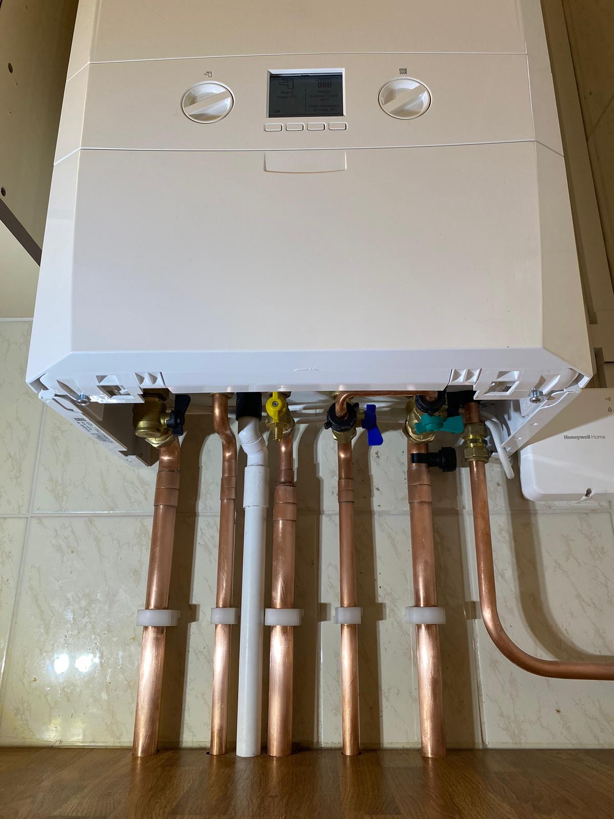 Underside of a new boiler installation showing the copper tails and isolation valves